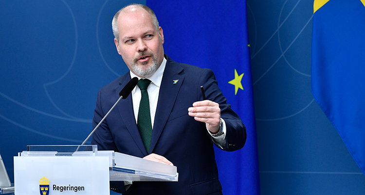 Johansson står i en talarstol där det står Regeringen. Han pratar och tittar åt sidan.