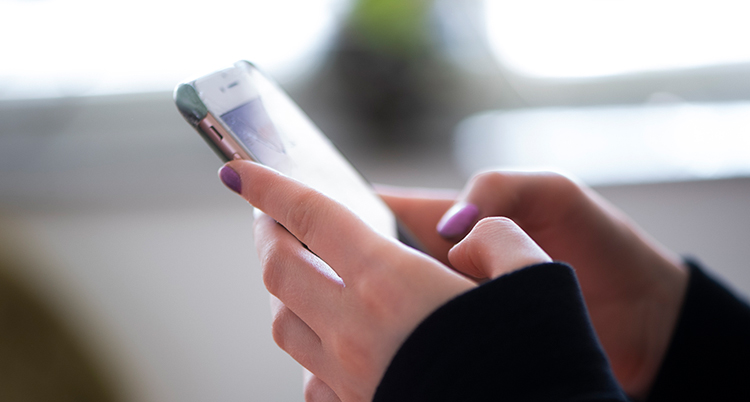 Två händer skriver på en mobiltelefon.