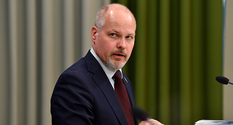 En nära bild på ministern. Han tittar år sidan och är allvarlig.
