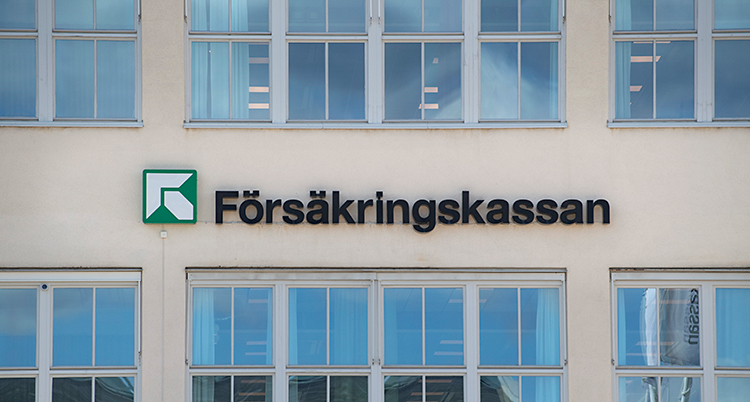 En bild på ett stort vitt hus. Det finns en skylt på väggen. Där står det Försäkringskassan.