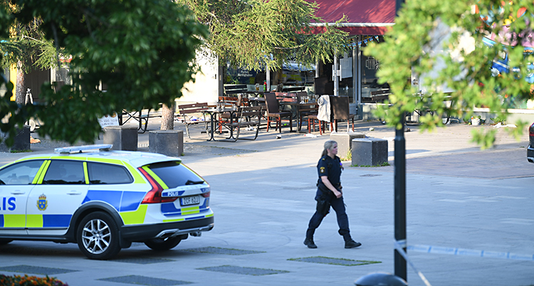 Från Sätra centrum. Där står en polisbil och en polis går omkring. I bakgrunden syns en pizzeria som har en uteservering.