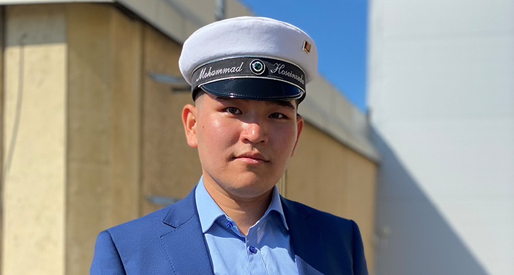 En nära bild honom i vit studentmössa.