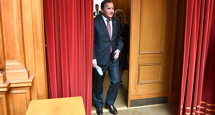 Stefan Löfven går igenom en dörr.