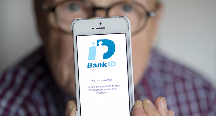 en äldre man håller fram sin mobil med ett bankid