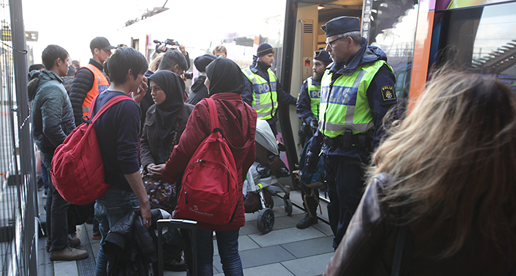 Utanför en tågstation. Där står flera människor och några poliser.