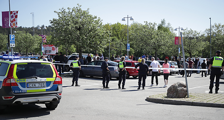 En parkeringsplats i Hjällbo. Poliser är ute och jobbar. De har spärrat av platsen med ett band.