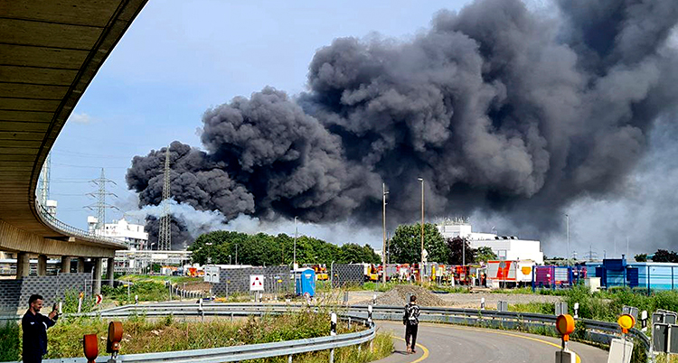 En väg i staden Leverkusen. Längre bort syns ett stort moln med svart rök.