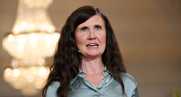 Hon talar och har en liten mikrofon bakom örat.