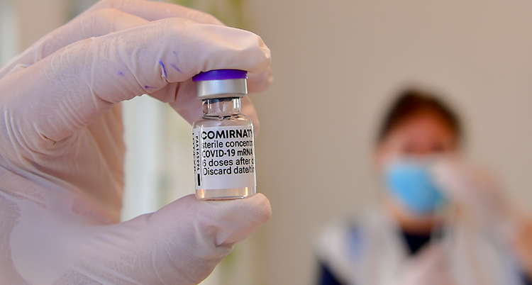 en hand håller i en flaska med vaccin.