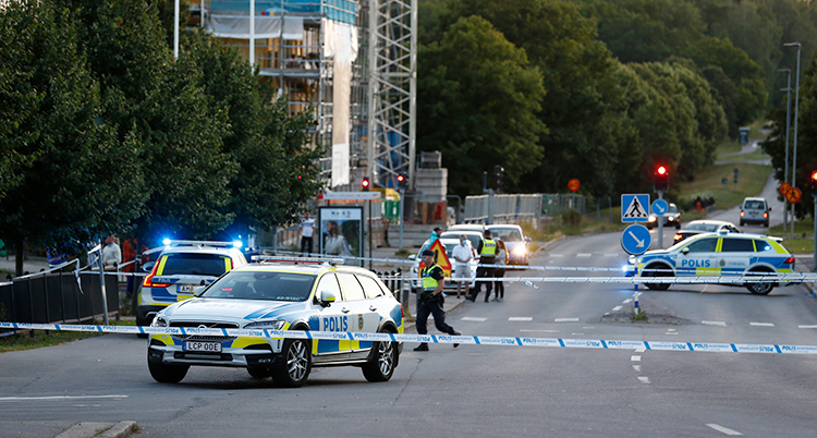 Flera polisbilar står på en gata. Över gatan går blå och vita band som poliserna satt upp.