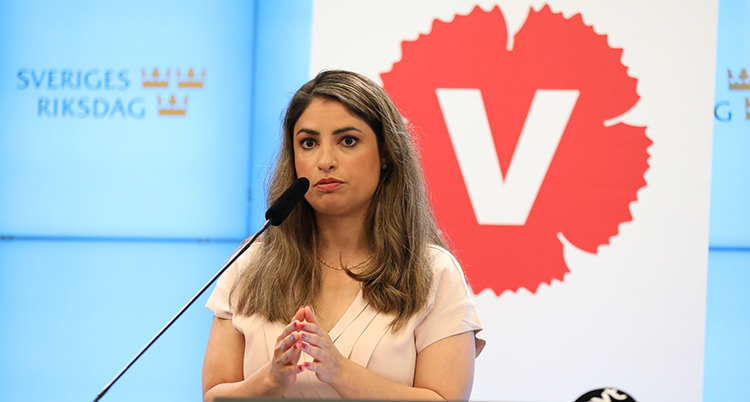 Dadgostar talar. Bakom henne är Vänstertpartiets röda märke.