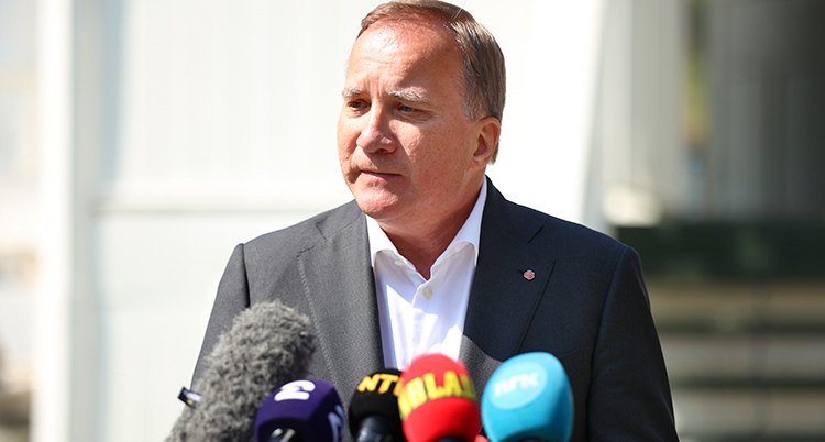 Löfven har en rad mikrofoner framför sig. Bara överkroppen är med på bilden. Han tittar snett åt sidan och ser allvarlig ut.