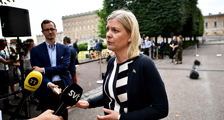 Andersson talar. Några mikrofoner hålls framför henea.
