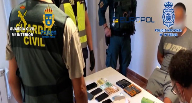 Ryggen på en polis syns och på ett bord framför ligger droger.