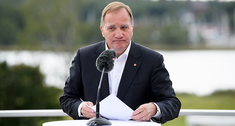 Löfven ser sammanbiten ut. Han står i en talarstol med en mikrofon framför sig.
