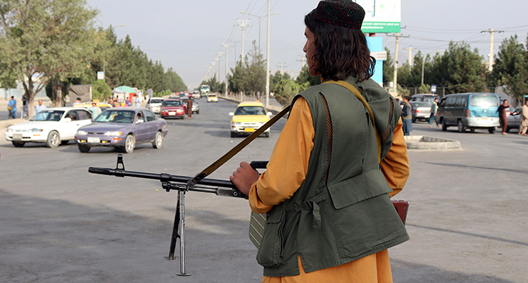 en taliban står på en trafikerad gata och håller i ett gevär.