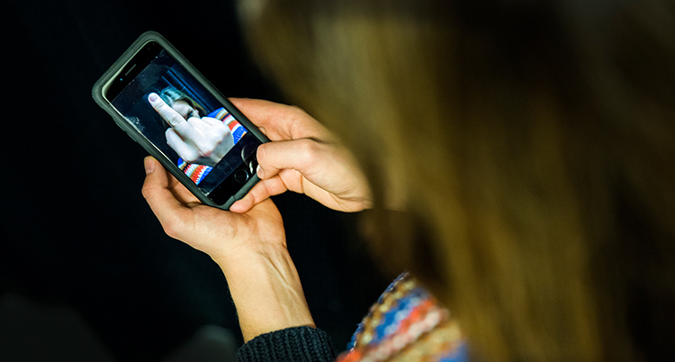 En kvinna tittar på en bild på sin mobil. Bilden visar en person som gör 