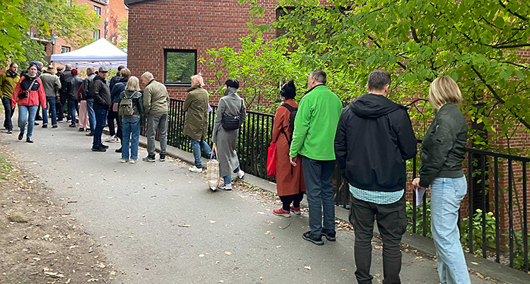 Människor står i kö utanför en kyrka.