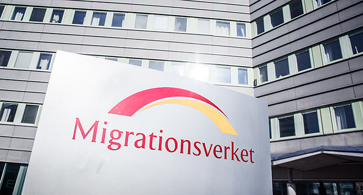 En skylt där det står Migrationsverket. Skylten står utanför ett stort hus.