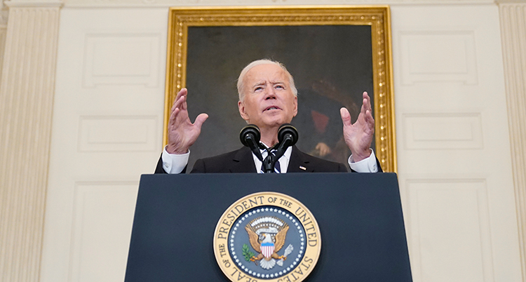 Biden i en talarstol. Han håller upp händerna.