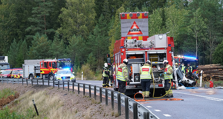 En bilväg där det står brandbilar och en polisbil.