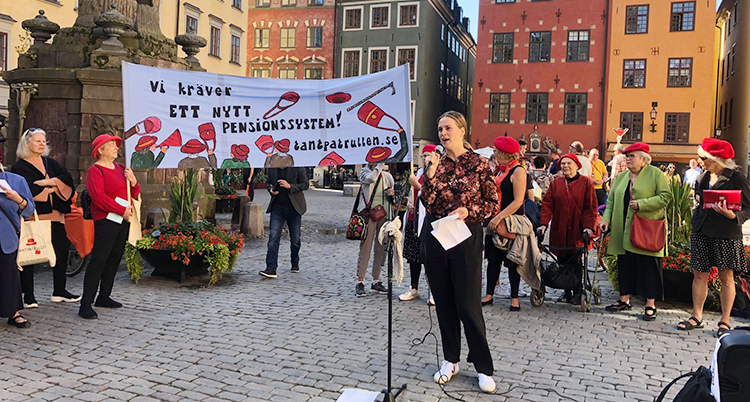 Flera kvinnor i röda baskrar på huvudet står på ett torg.