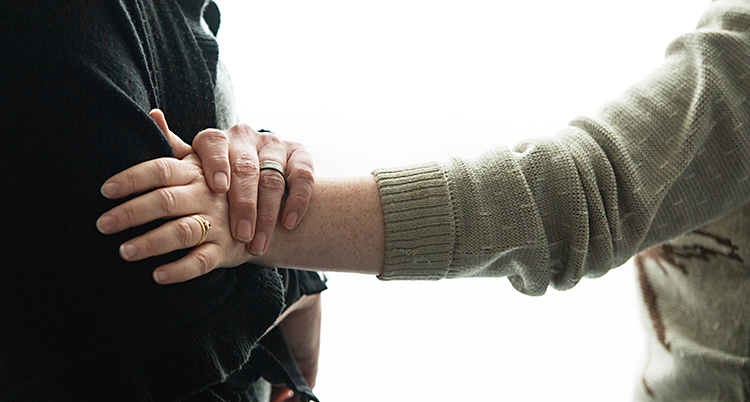 En person lägger sin hand på en annan persons arm.