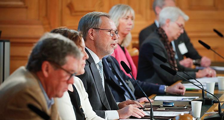 Flera personer sitter på en rad. De har mikrofoner framför sig.