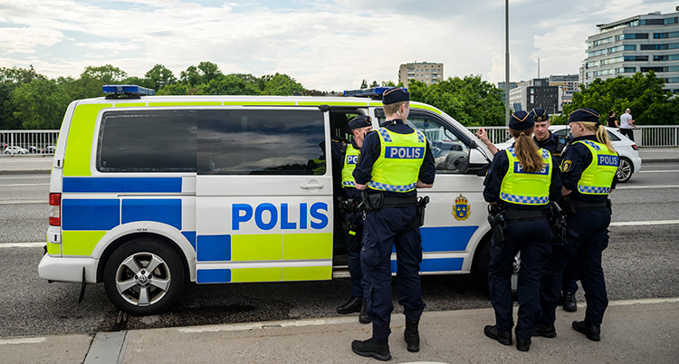 Poliser utanför en polisbil.