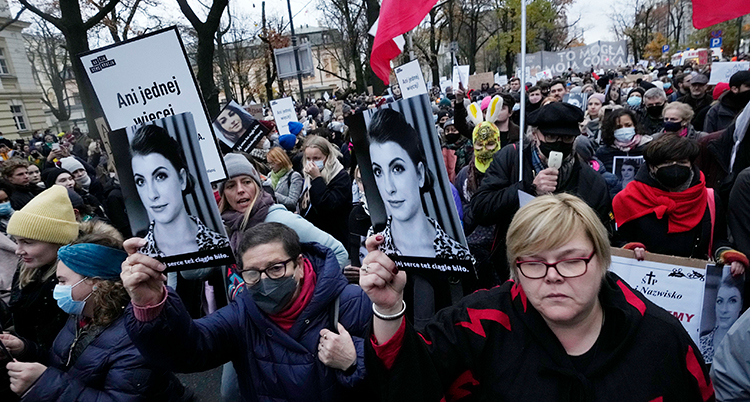 massor av människor protesterar. Många håller upp bilder på kvinnan som dog.