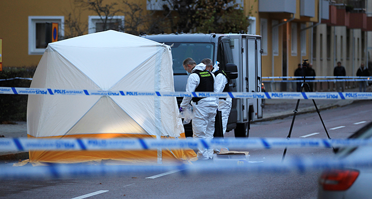 Poliser har spärrat av en gata. Där står en bil och ett tält. Personer jobbar vid tältet.