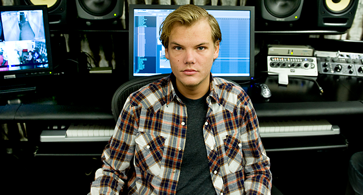 Han sitter i en studio. Han tittar in i kameran.