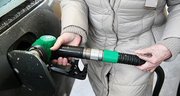 En person håller i en pump och stoppar in den i sin bil.