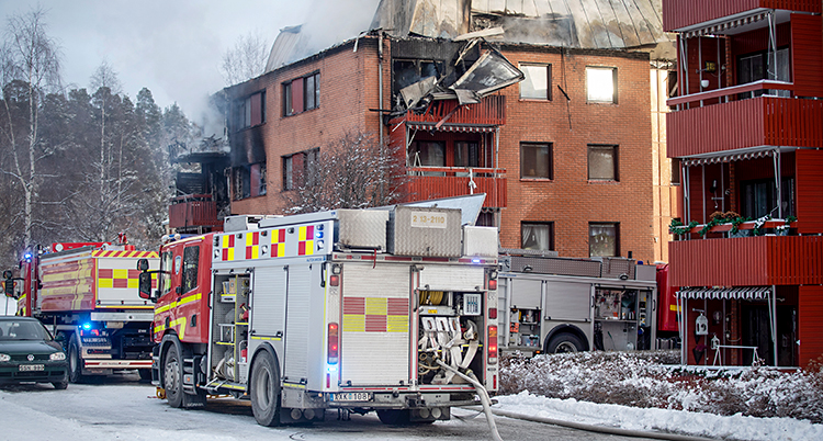 Flera brandbilar står utanför ett hus med lägenheter.