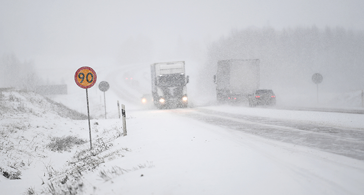 Bilar som kör på en väg. Det snöar mycket.