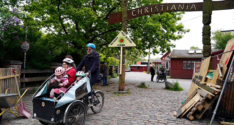 En man cyklar med en flakcykel där det sitter tre personer.