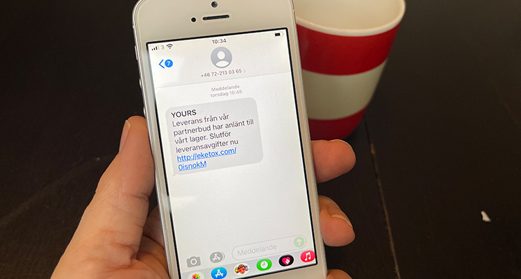 En hand håller en mobil med ett falskt meddelande.
