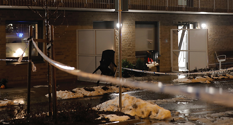 Det är mörkt ute. Poliser har satt upp band utanför ett hus med lägenheter.