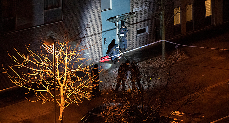 Det är mörkt. Några poliser jobbar vid ett hus.