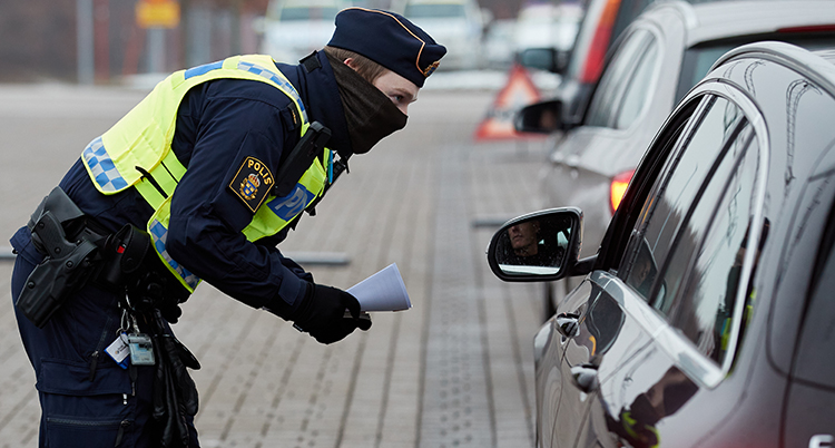 en polis böjer sig fram mot en bilruta.
