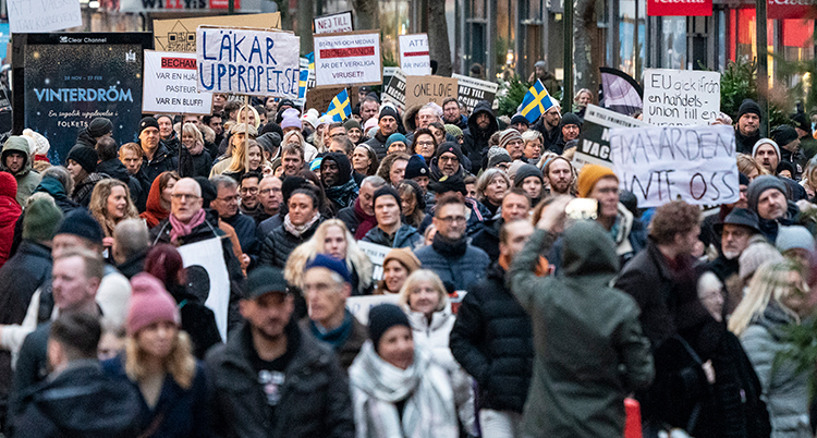 Massor av människor står nära varandra. En del har skyltar i händerna.