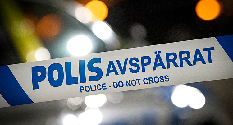 Närbild på ett band som poliser har satt upp utomhus. Det står Polis avspärrat på bandet.