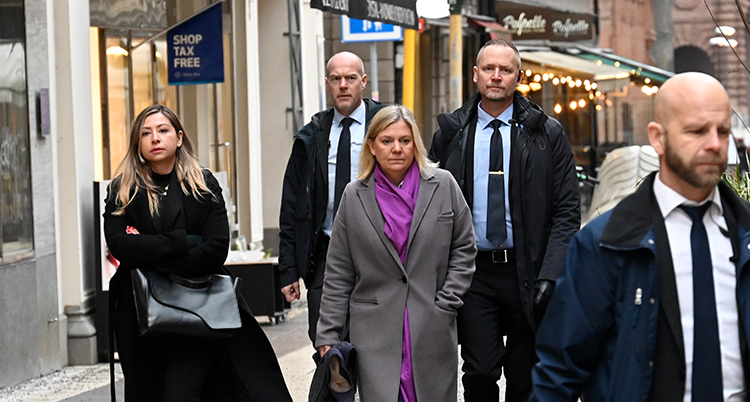 De går på en trottoar. Hon går mitten av flera personer