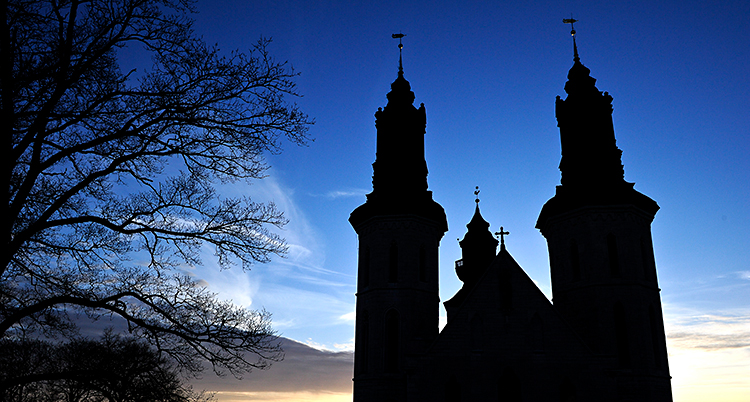 Solen är på väg att gå ner. Vi ser Visby domkyrka som en mörk siluett.