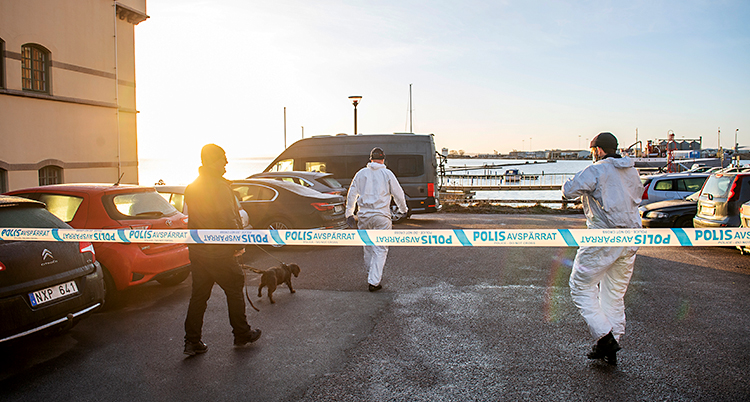 Poliserna har spärrat av med band. Innanför bandet är en massa bilar och tre poliser.