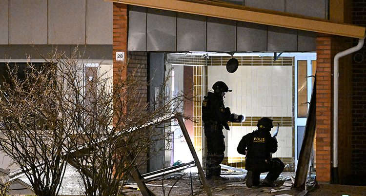 Poliser undersöker en skadad port.