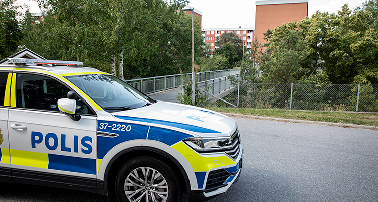 En polisbil med en gångbro i bakgrunden.