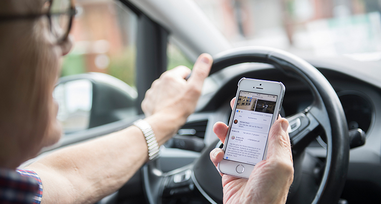 En person som stur med en hand och håller mobilen i den andra.