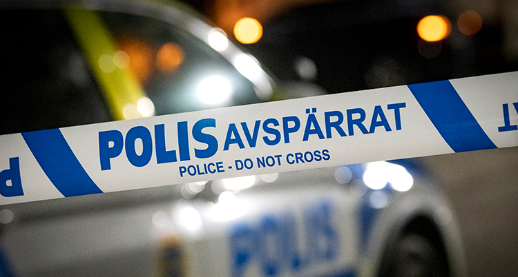Ett band där det står Polis avspärrat. I bakgrunden polisbilar.