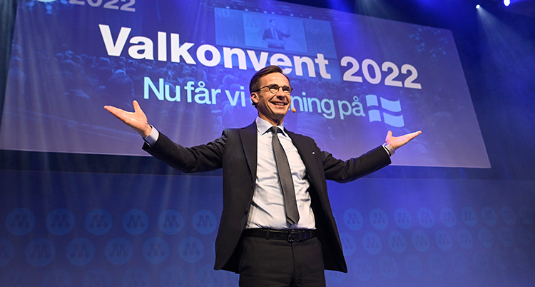 Kristersson sträcker ut armarna och ler.